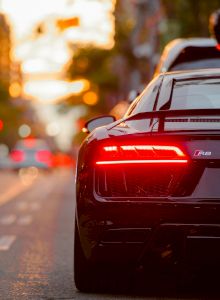 A crowded city street at night with red taillights, cars bumper to bumper, and blurred city lights in the background.